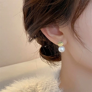 Close-up of minimalist gold geometric pearl drop earrings worn by a model