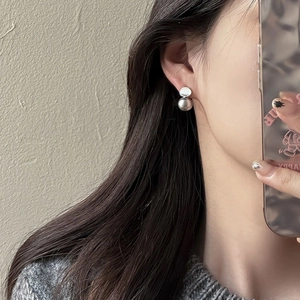 Close-up of minimalist silver geometric double sphere earrings worn on a model ear