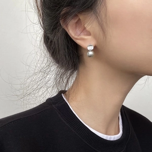 Close-up of a minimalist pearl earring on model featuring a silver metal base