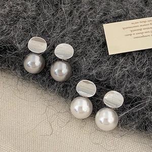 Close-up of geometric silver pearl earrings in grey and cream on textured fabric