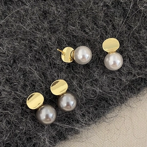 Elegant geometric gold stud earrings with white and dark grey round pearls on wool fabric
