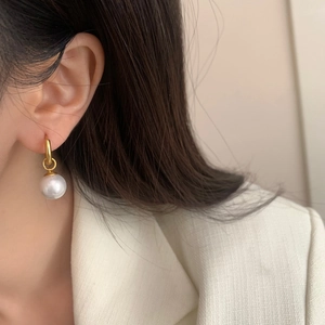 Detailed view of large white pearl drop earrings with minimalist gold metal hoops