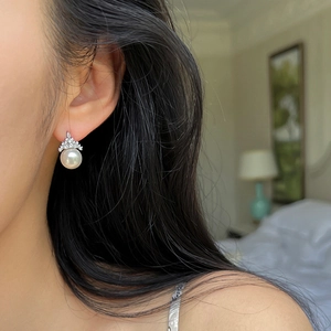 Close-up of crown-shaped pearl earring with zircons worn for an elegant look