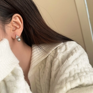 Close-up of elegant grey pearl earring with crown-shaped zircon setting on model ear