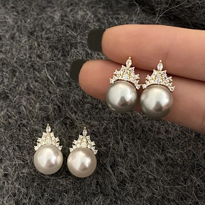 Macro detail of crown-shaped pearl earrings with sparkling micro-pave cubic zirconia