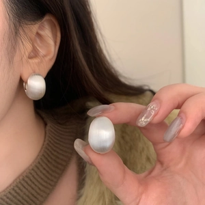 Détail de boucles d'oreilles boules en argent mat avec texture brossée sur modèle