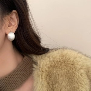 Gros plan de boucles d'oreilles dôme en argent brossé minimalistes portées par un mannequin
