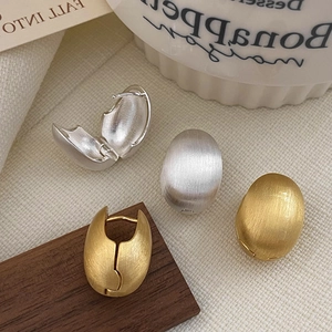 Détail de boucles d'oreilles créoles ovales mates brossées en fini or et argent