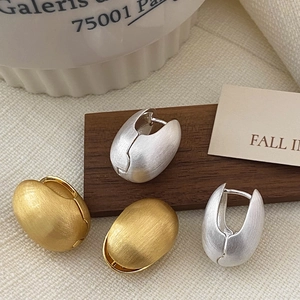 Gros plan de boucles d'oreilles grains de café brossés en finition dorée et argentée chic