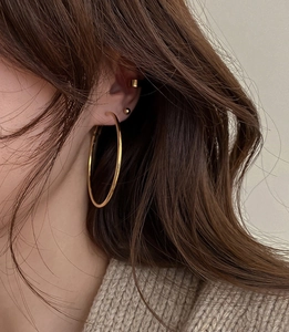 Nahaufnahme von goldenem Creolen-Ohrring, Stecker und Ohrmanschette am Modell