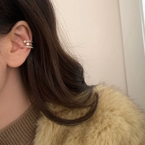 Detail of gold multi-layer ear cuff with zircon star design worn on ear cartilage