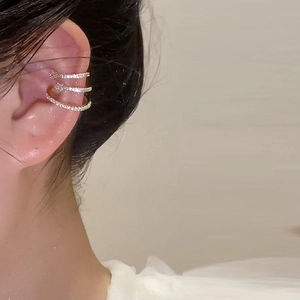 Close-up of triple-layered gold ear cuff with pavé zircons and star details on model
