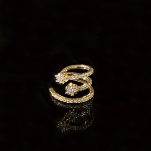 Macro shot of gold spiral ear cuff with sparkling zircons and star details on black background