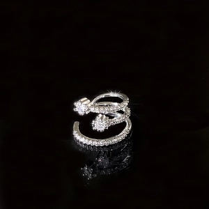 Macro shot of silver triple-layer star ear cuff with pavé zircon stones on dark background
