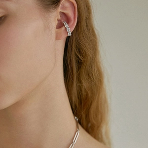 Détail d'un ear cuff argenté avec des cristaux étincelants sur le cartilage d'un mannequin