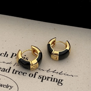 Detailed view of French style C-shape gold earrings with black enamel on vintage paper