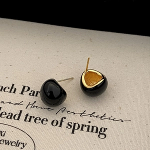 Detail view of gold bean earrings with black enamel and 925 sterling silver hallmark
