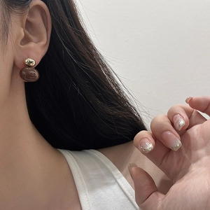 Close-up of a woman wearing vintage burgundy drop earrings with gold metallic sphere studs