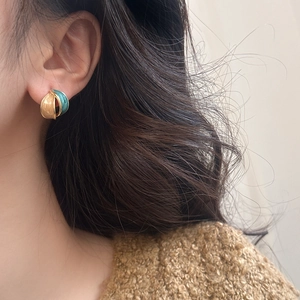 Detail of retro enamel petal earrings in gold, cream, and teal on model's ear