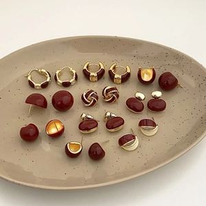 Elegant burgundy and gold earring set with enamel finish on a ceramic tray display