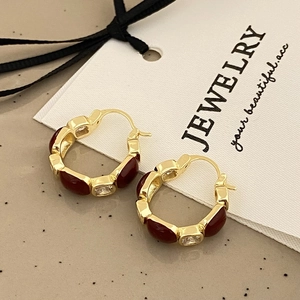 Close-up of vintage gold hoop earrings with red enamel and shimmering cubic zirconia stones