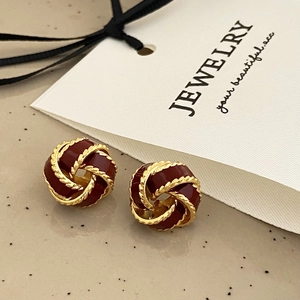 Close-up of vintage knot earrings in gold finish with deep red glazed enamel centers
