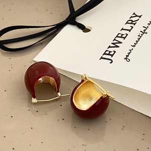 Close-up of burgundy enamel hoop earrings with golden inner lining and retro design