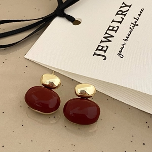 Detail shot of vintage burgundy oval drop earrings with polished gold-tone metal accents