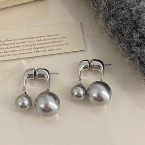 Close-up of elegant double grey pearl drop earrings with silver hooks on stone