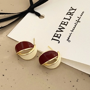 Macro view of geometric wine red and cream enamel earrings with a gold metal frame