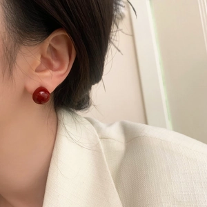 Classic elegant red spherical earrings worn by a model in a stylish cream blazer