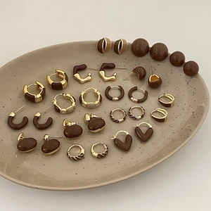 French vintage brown enamel earrings collection in gold and caramel hues on a ceramic plate