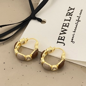 Detail of brown and beige enamel hoop earrings with inlaid crystals in golden finish