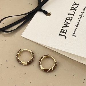 Detailed macro shot of vintage gold twist hoop earrings with brown enamel finish