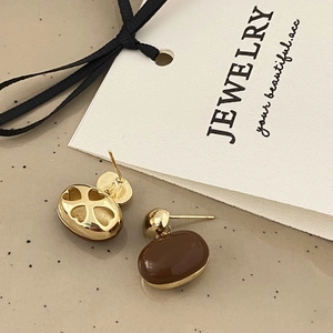 Detailed close-up showing heart and flower hollow-out design on back of gold earrings