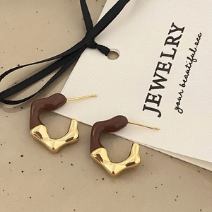 Macro detail of French vintage earrings with gold metal and brown enamel finish