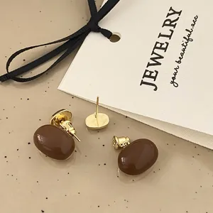 Macro shot of French retro coffee brown drop oil earrings with elegant gold metal base
