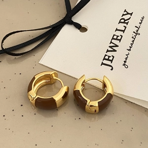 Macro detail of French vintage C-shaped gold hoop earrings with brown enamel finish