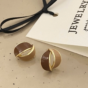 Close-up of brown and beige enamel earrings with gold plating and luxury texture