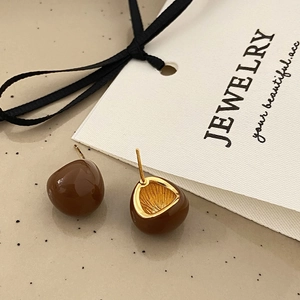 Macro shot of brown bean-shaped resin earrings with detailed hollow metal interior texture