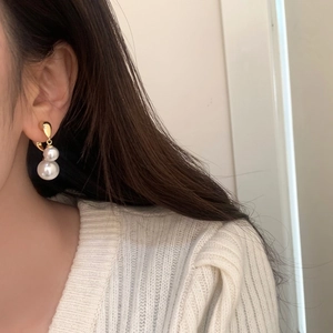 Detail of luxury double pearl drop earrings featuring elegant gold-tone metal and pearl luster