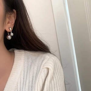 Close-up of elegant silver earrings with double grey-purple pearls worn by a model