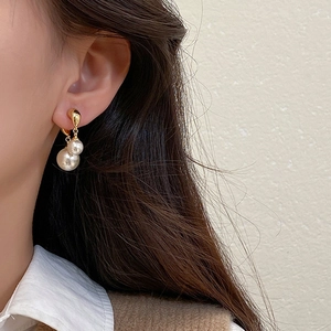 Close-up of elegant gold pearl drop earrings worn by a model for a classy look