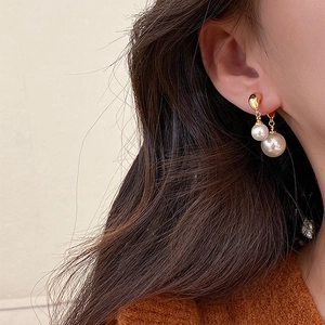 Close-up of elegant double pearl drop earrings in gold finish worn by a model