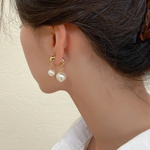 Detailed view of elegant gold metal hook earrings with double pearls on a model