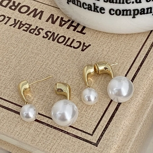 Close-up of elegant gold pearl earrings on vintage book and ceramic cup background
