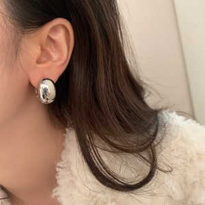 Close-up of a chunky silver eggshell stud earring on a model with a minimalist design