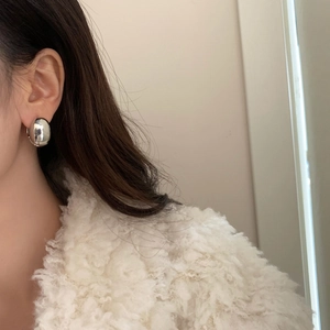 Detail shot of silver eggshell hoop earrings on model wearing a white fuzzy coat