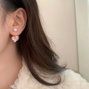 Gros plan de boucles d'oreilles cœur rose avec grande perle arrière sur un modèle