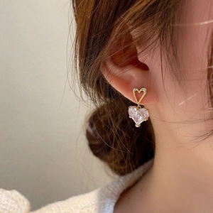Gros plan de boucles d'oreilles cœur en perle avec clous dorés ajourés sur modèle